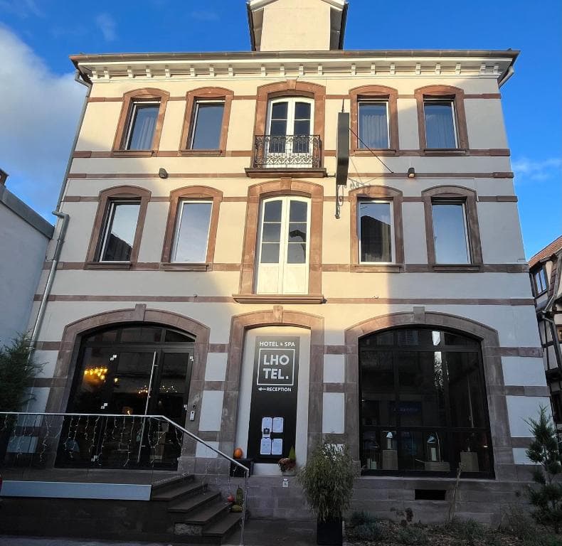 Hotel & Spa LHO TEL. building facade with stone trim and small balcony under blue sky.
