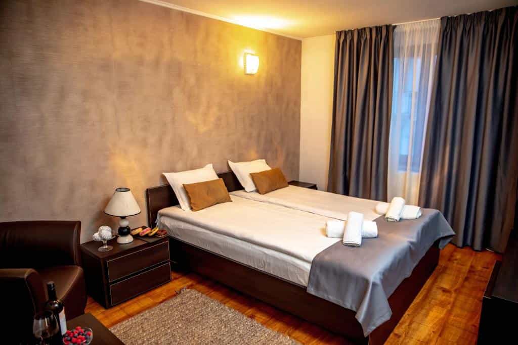 Twin beds in hotel room with dark wood furniture and textured brown accent wall
