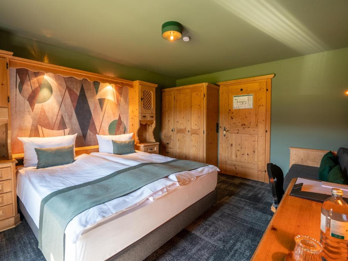 Hotel room with twin beds, wooden furniture, and green walls at Berghotel Sonnenbichl