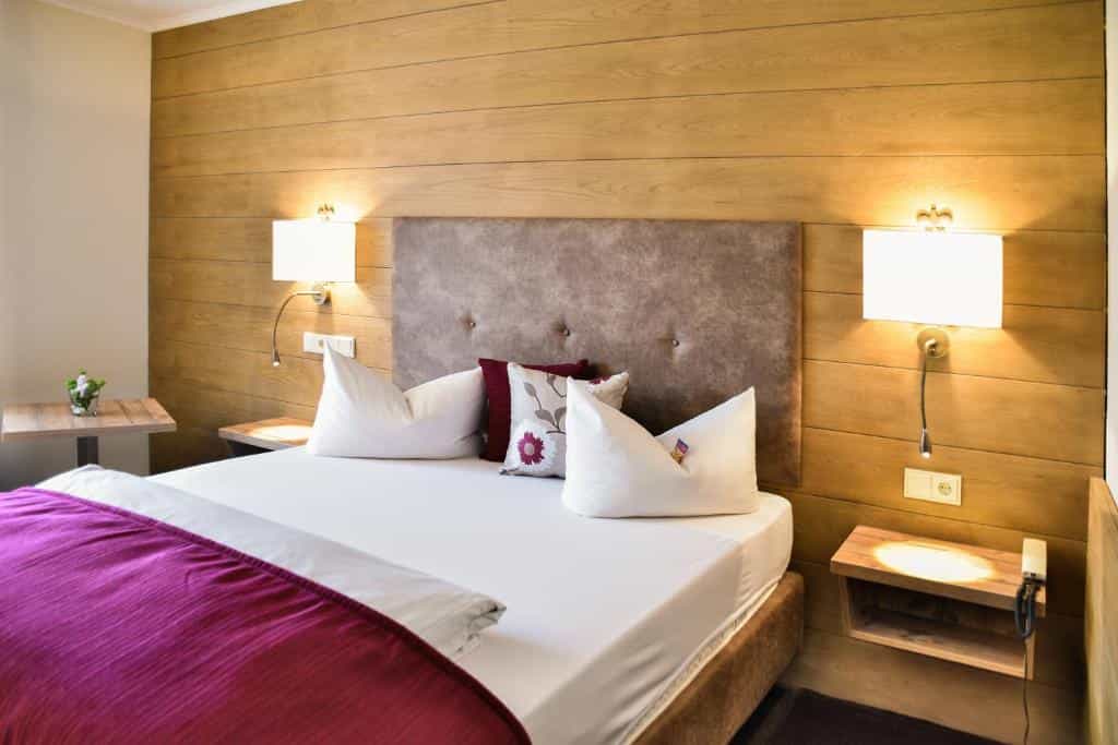 Bedroom with wood paneling, white bedding, and a magenta throw, likely in Gästehaus am Kurpark.