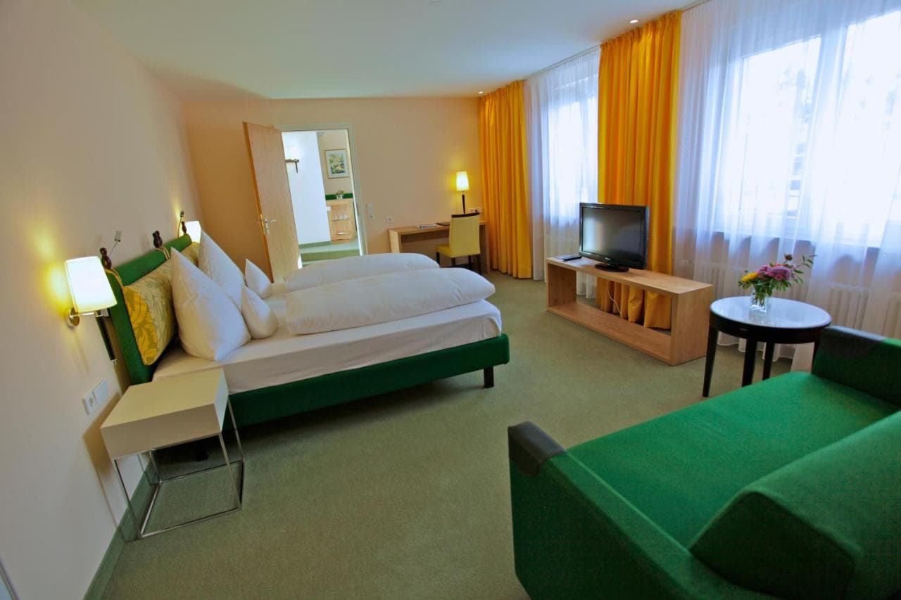 Parkhotel Flora am Schluchsee room with green bed and yellow curtains.