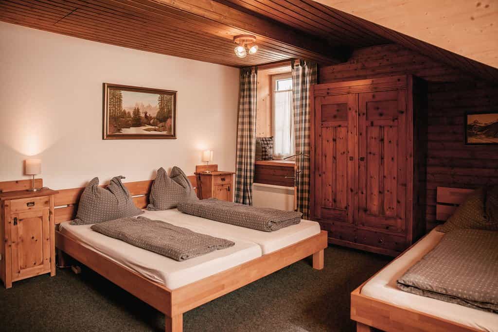 Cozy wooden attic bedroom with twin beds, plaid curtains, and rustic furniture