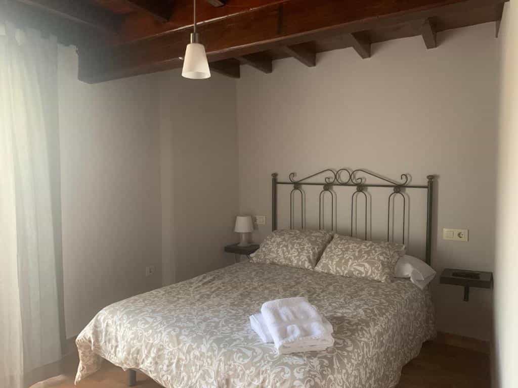 Bedroom with double bed, patterned bedding, and exposed wooden ceiling beams at Albergue Ponte Olveira.
