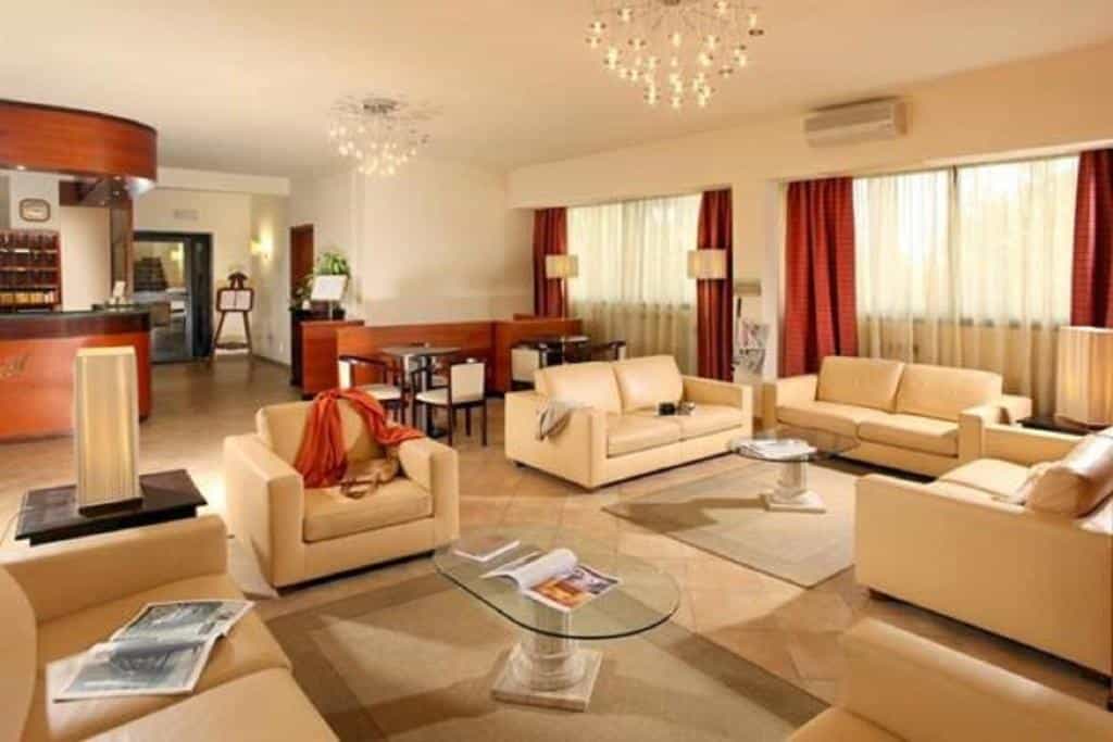 Hotel Cassia lobby with beige leather seating, glass coffee tables, and reception desk.