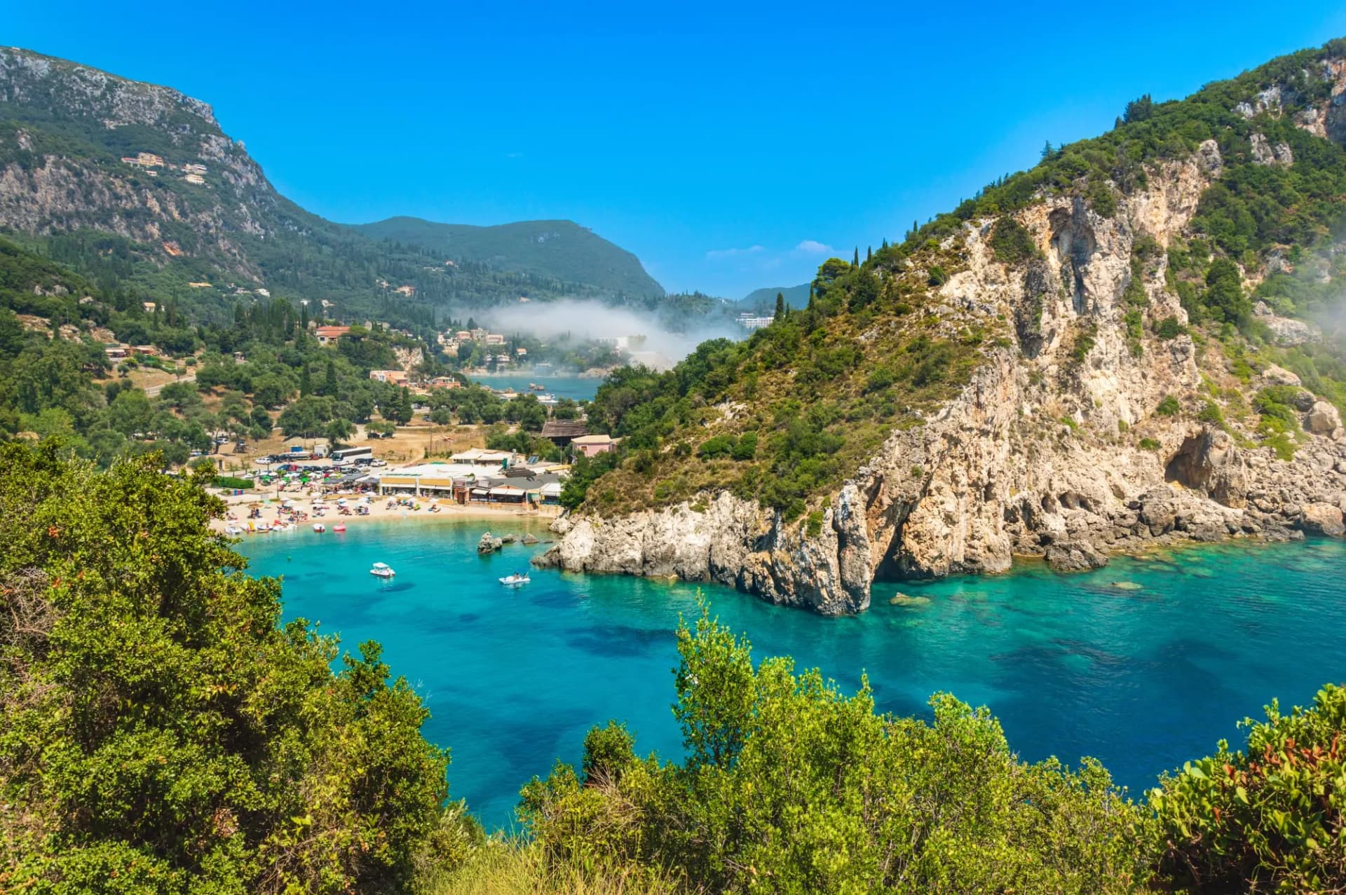 Paleokastritsa beach and village on Corfu island, Greece. Picturesque seashore with turquoise crystal water, pebble beach Agios Spiridon, mountains and cliffs