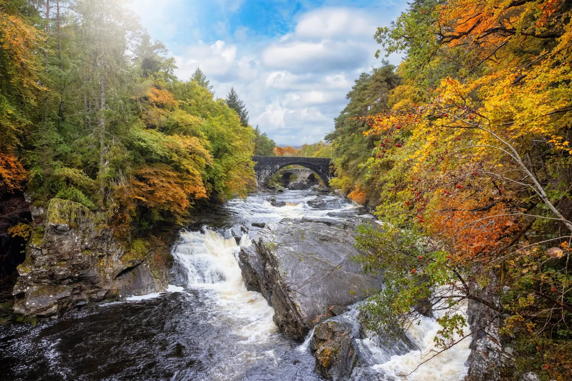 The beautiful Invermoriston Falls during autumn time with golden leaves and sunlight, Highlands, Scotland