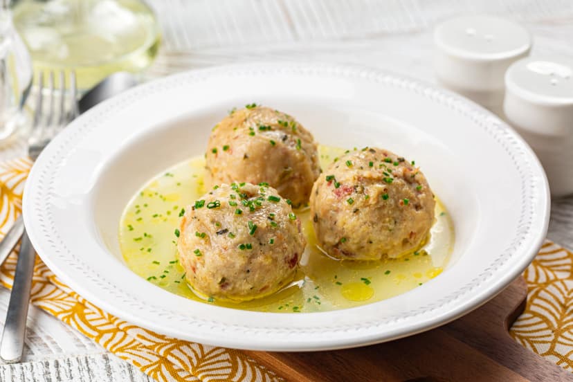 Canederli or Knödel in broth with green onion, typical pasta or dumplings for Alps, Alto Adige, German, Italian, Austrian cuisine. Made from stale bread, milk, eggs, speck..