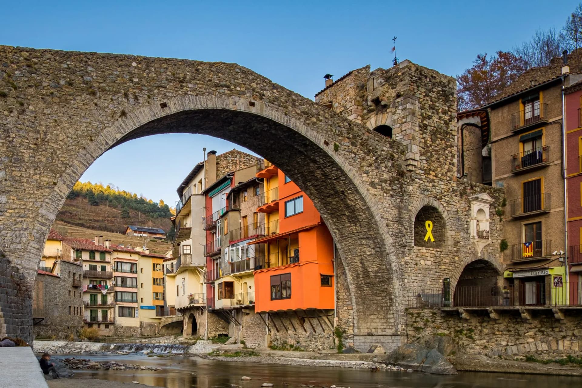 Stone medieval bridge over river in Camprodon town, Gerona, Spain with colorful buildings.
