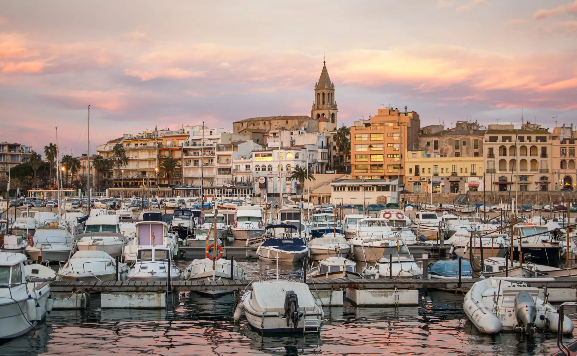 Fishing and leisure boats in the marina at Palamós under a pink evening sky
