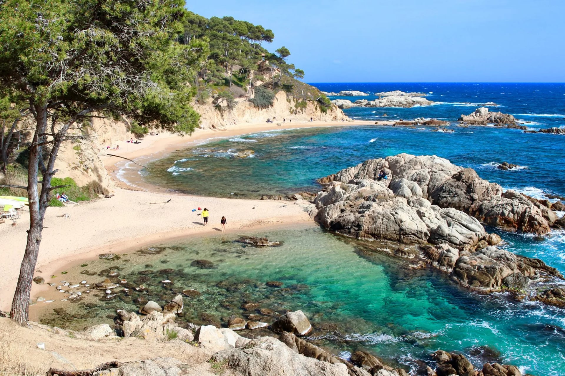 Turquoise water and pale sand in the sheltered cove of Cala Estreta backed by pines and rock