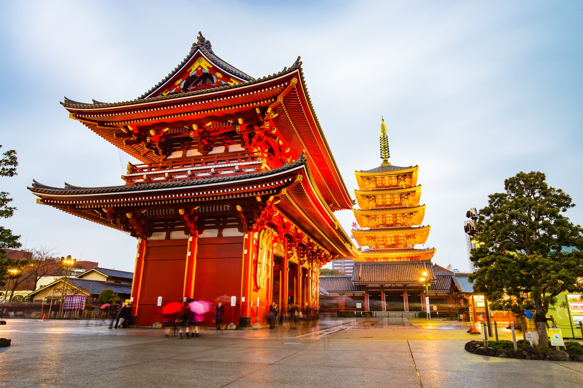 Illuminated red temple gate and five-story pagoda at dusk in Japan.