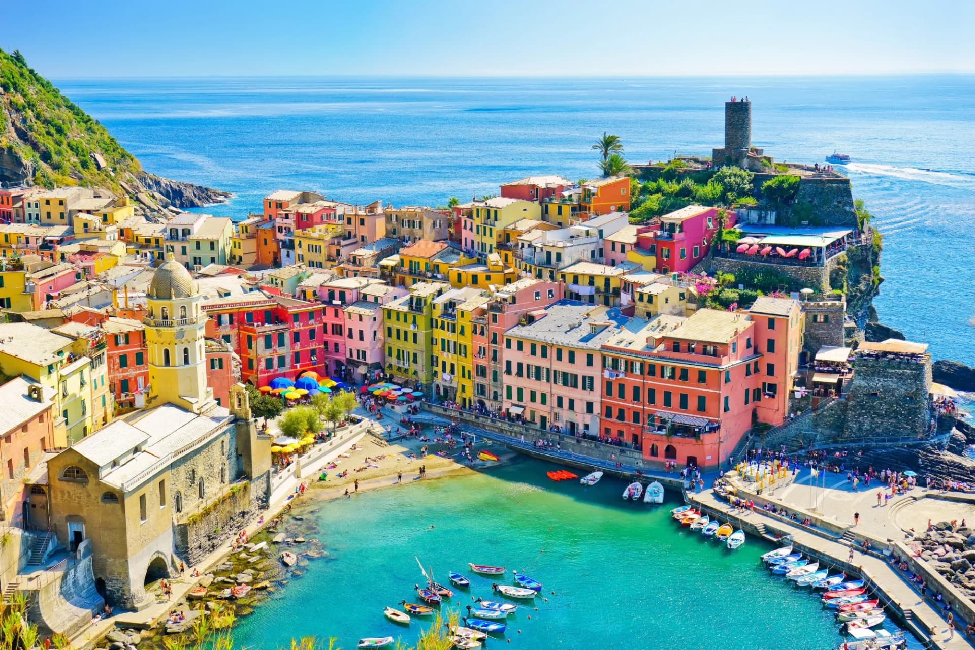 Colorful buildings of Vernazza village on the Mediterranean coast in summer with boats in the harbor.