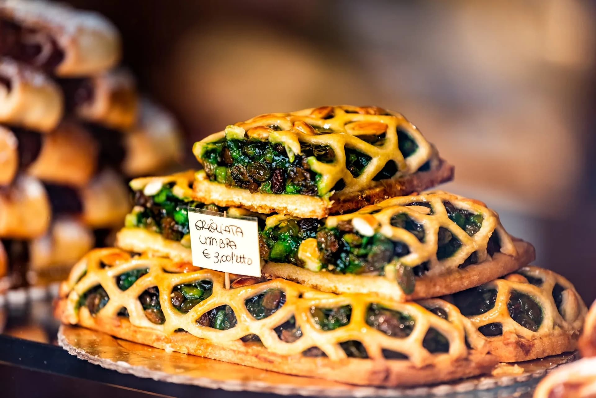 Colorful green baked lattice pastry tart dessert closeup in store window in Assisi in Umbria Italy on display in gourmet bakery Italian cafe with sign