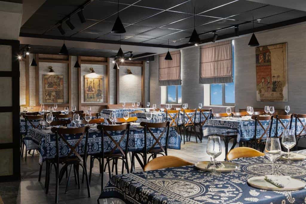 Restaurant dining room with wooden chairs and blue patterned tablecloths.