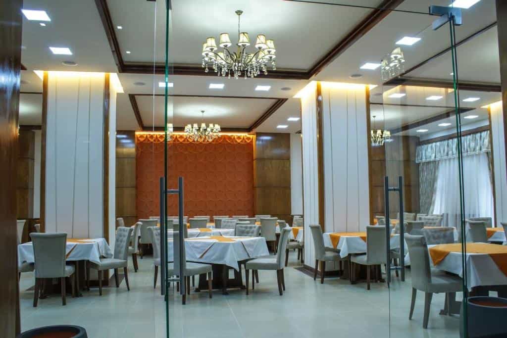 Dining room with tables, white tablecloths, and chairs in a modern hotel or restaurant interior.