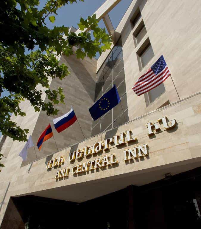 Ani Central Inn building facade with flags and stone exterior.