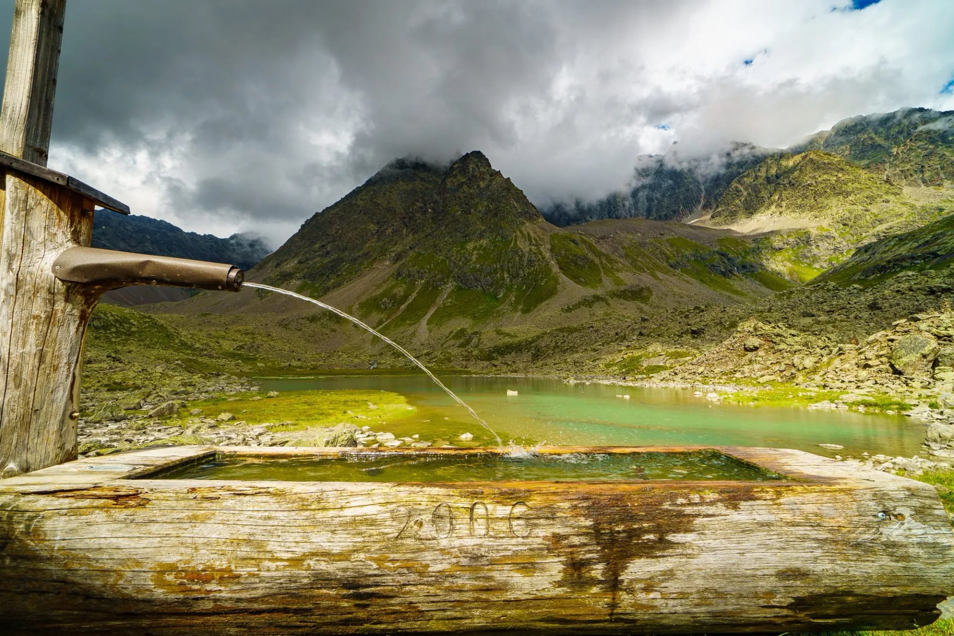 Water pouring from a spout into a wooden trough below a peak