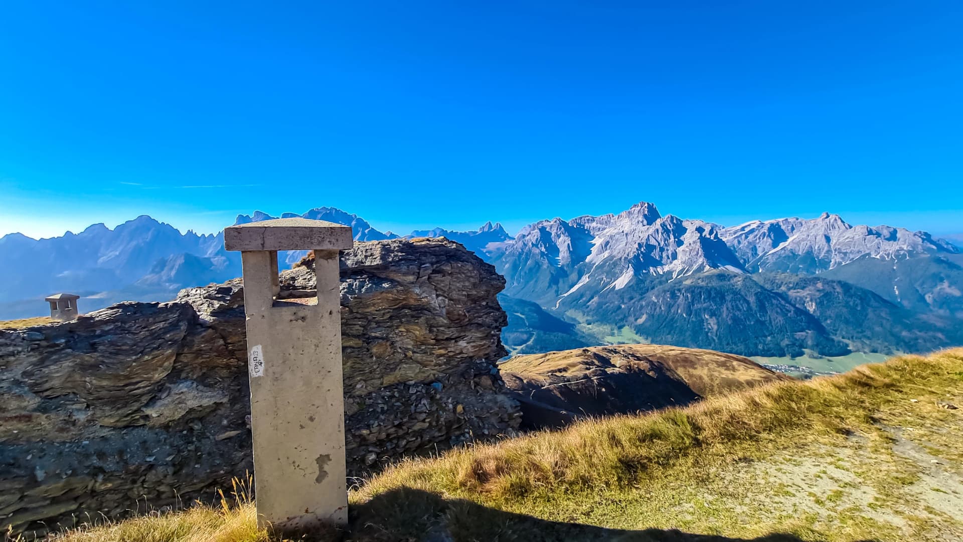 Hiking trail along remains of military bunker of First World War on mount Hornischegg with scenic view of mountain peaks of Sexten Dolomites, South Tyrol, border Austria Italy, Europe. Wanderlust Alps