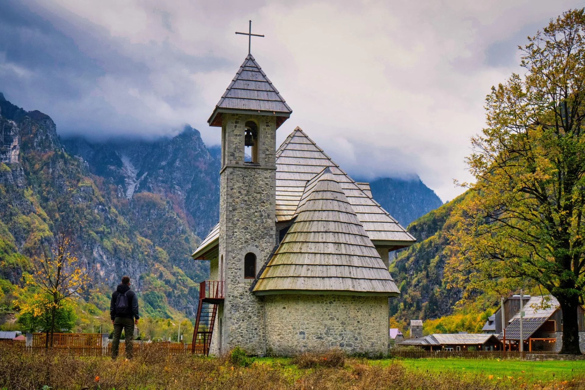 Stone church with wooden roof in Thethi National Park, Albania, with autumn colors and mountains.