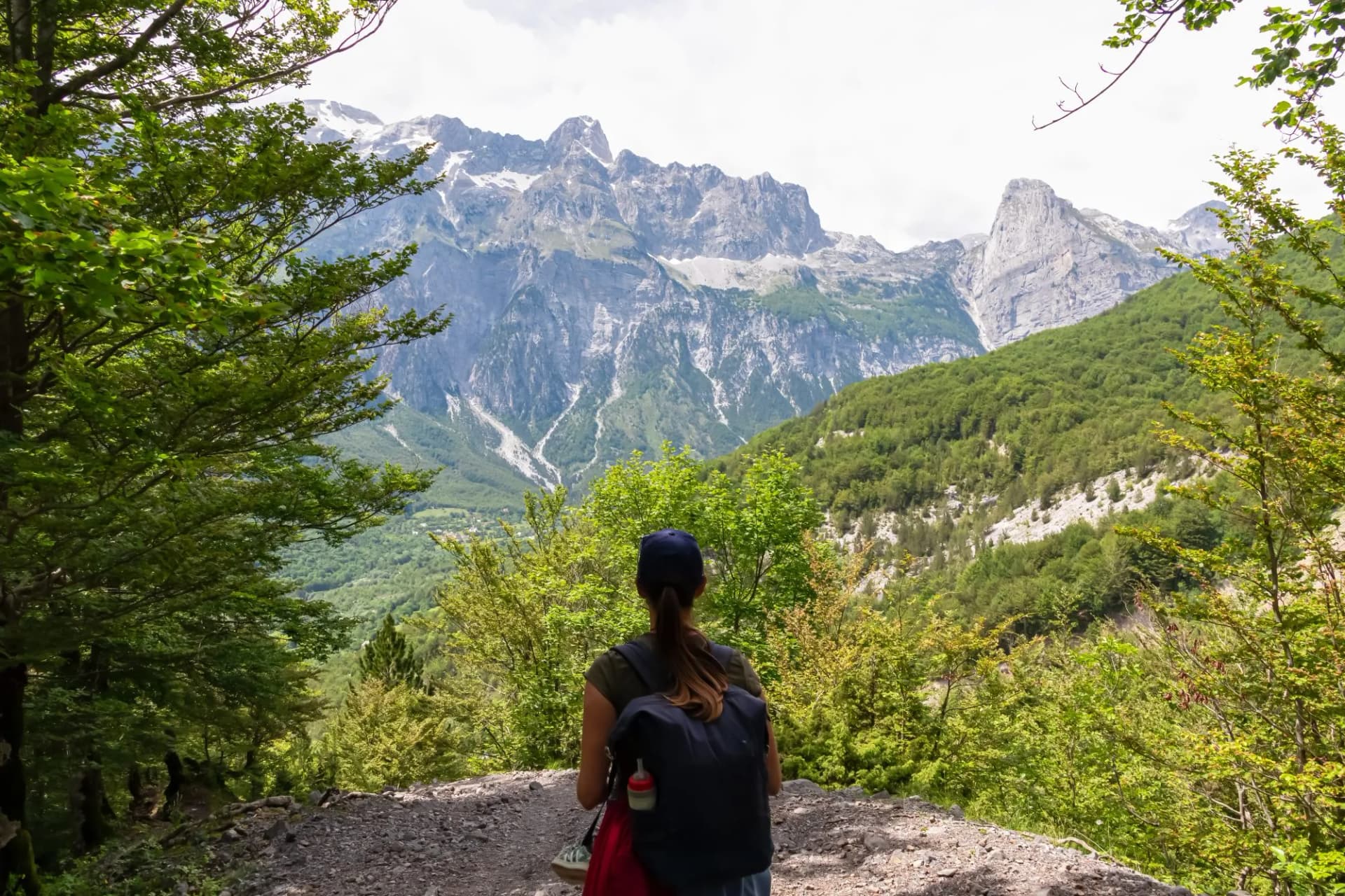 Hiker woman with panoramic of majestic mountain ridge massif Radohina, Albanian Alps (Accursed Mountains), Northern Albania. Scenic hiking trail from Valbona to Theth. Wanderlust in alpine wilderness