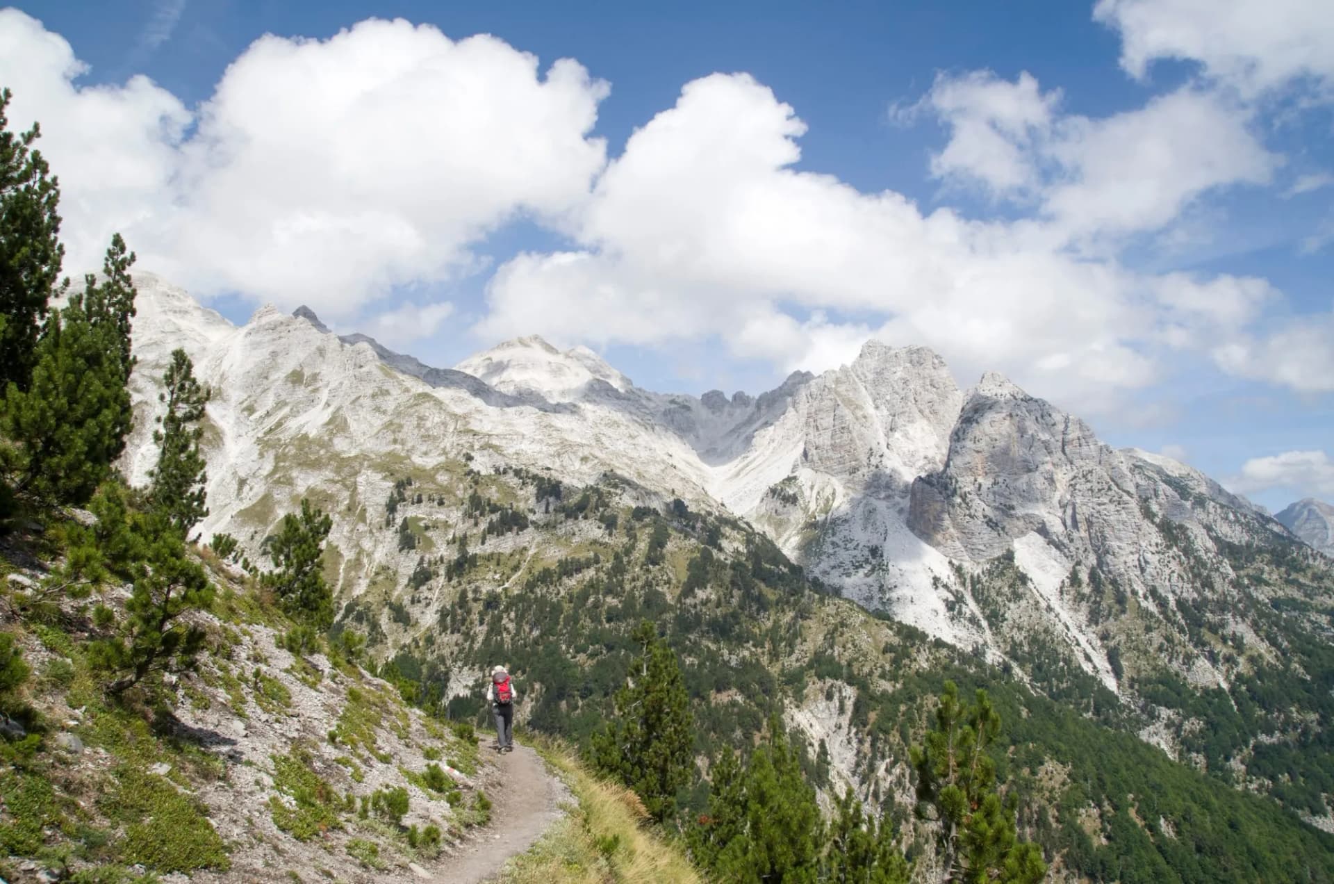 Hiker on trail with view of Jezerca summit in Albanian Alps from Valbona Pass