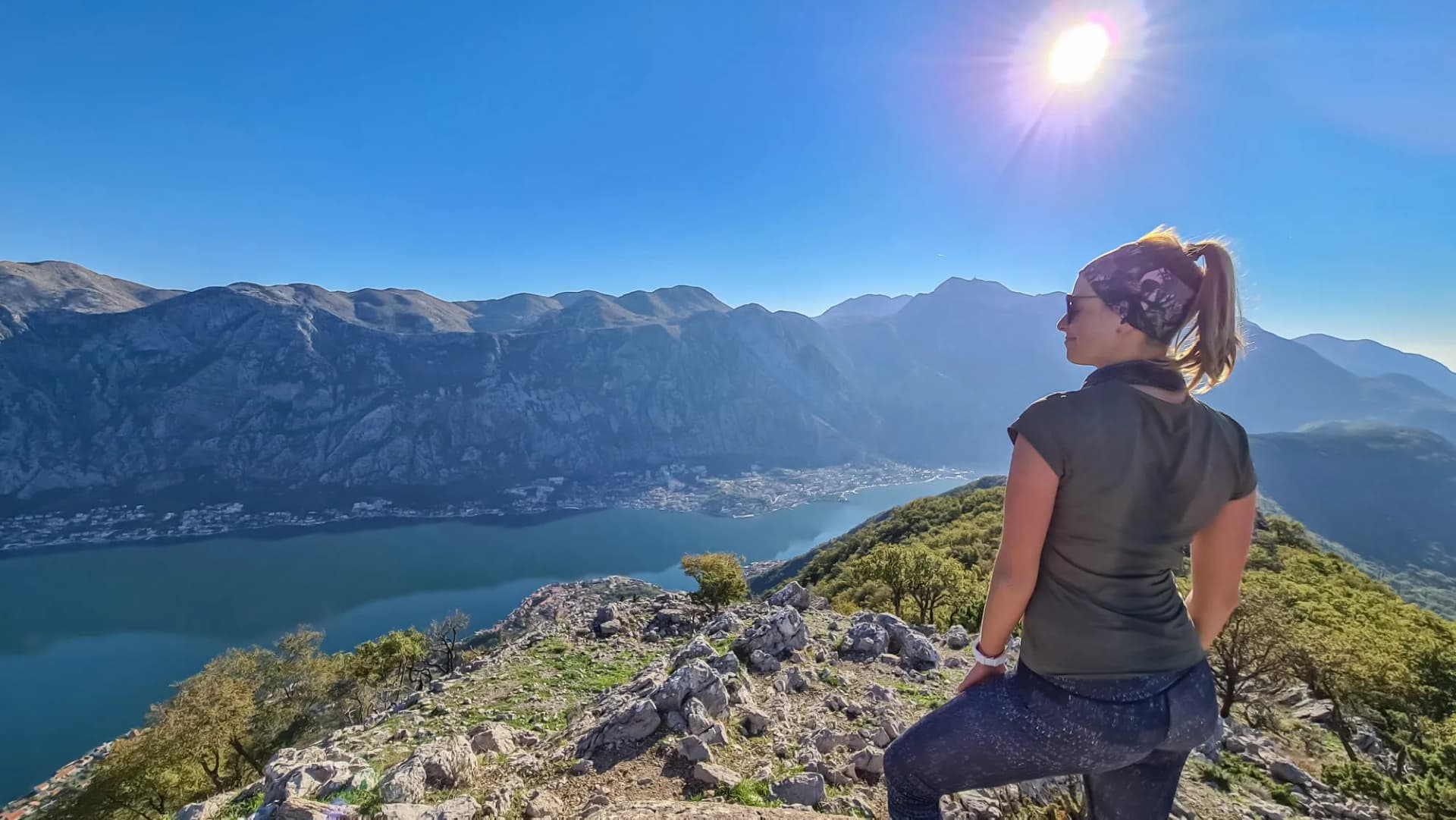 Woman with scenic view from mountain summit of Vrmac Sveti Ilija on Kotor bay in summer, Adriatic Mediterranean Sea, Montenegro, Balkans, Europe. Fjord winding along coastal towns. Hiking Dinaric Alps