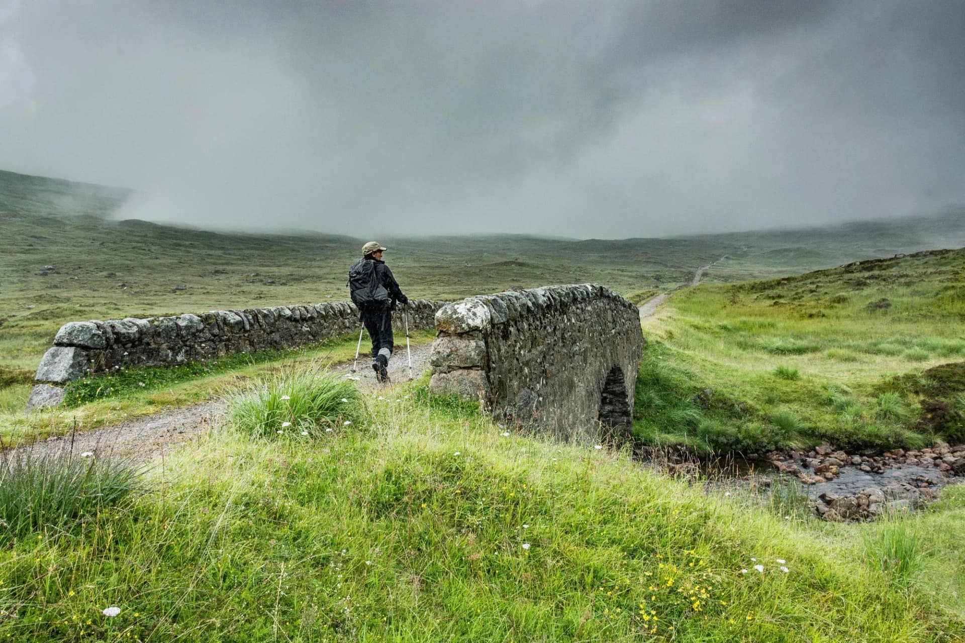 Along the West highland Way in Scotland. A hiker walks on an old stone bridge on the hiking trail which takes an old military road.