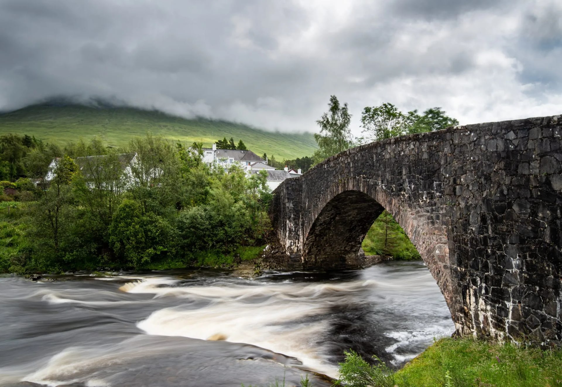The old stone bridge over the River Orchy with the village behind