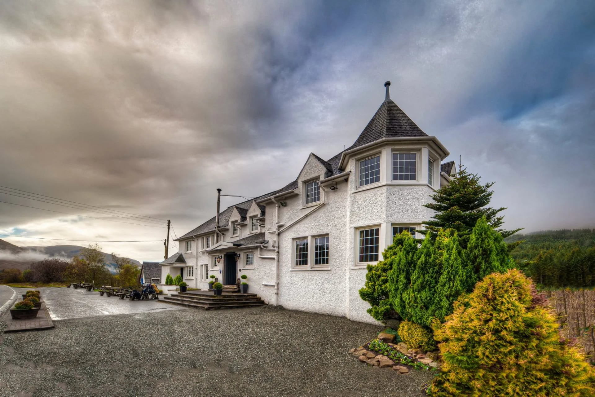 Het witte Bridge of Orchy Hotel onder een bewolkte lucht