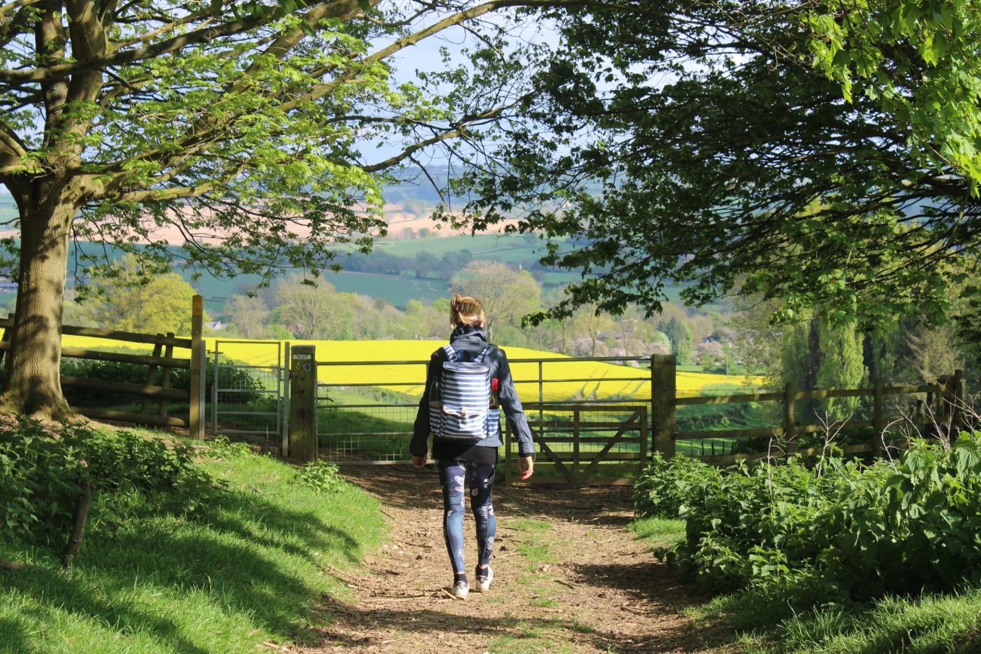 Walker with a daypack on a footpath through a field gate