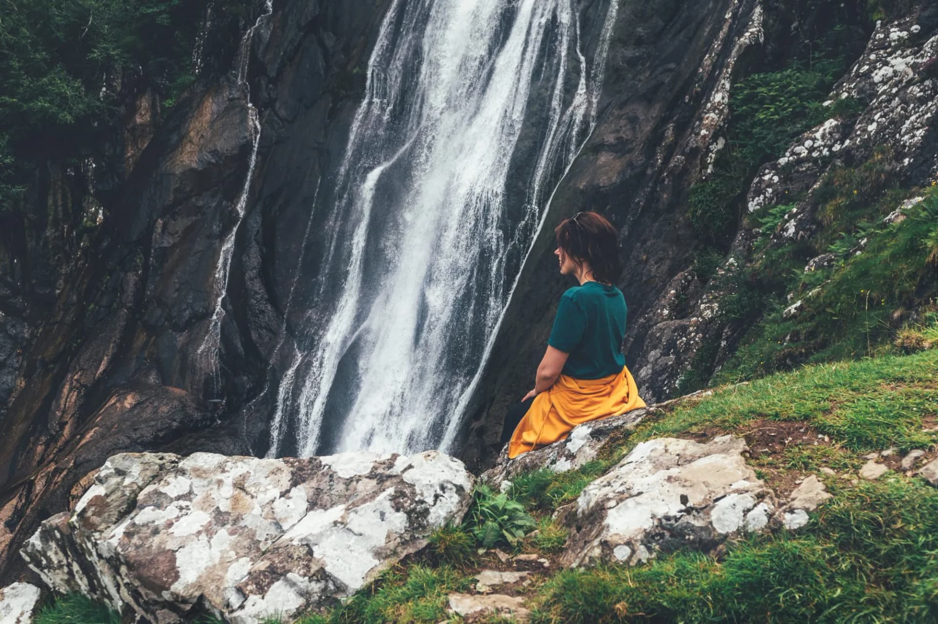 Young woman at Aber Falls or in Welsh Rhaeadr Fawr is waterfall located about two miles south of the village of Abergwyngregyn, Gwynedd, Wales