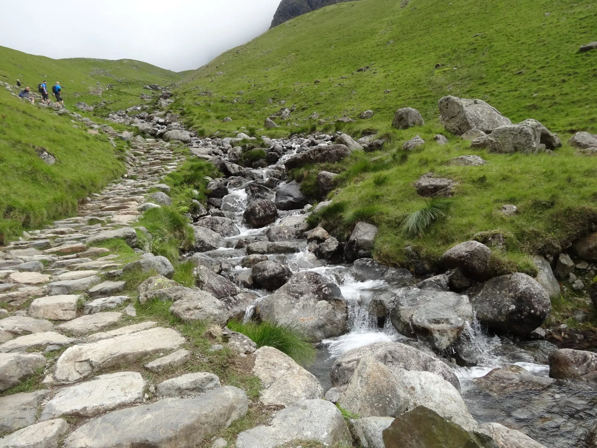 A hand pitched stone path climbing beside a rocky beck