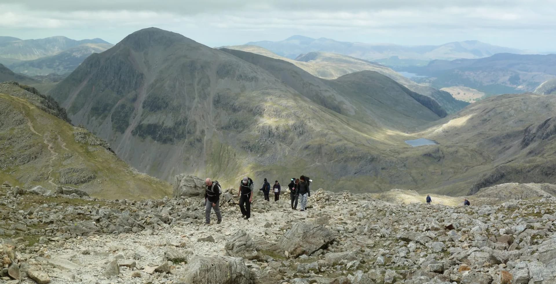Hiking on Scafell Pike looking back towards Great Gable, Sty Head Pass and Styhead Tarn in the Lake District, England, UK