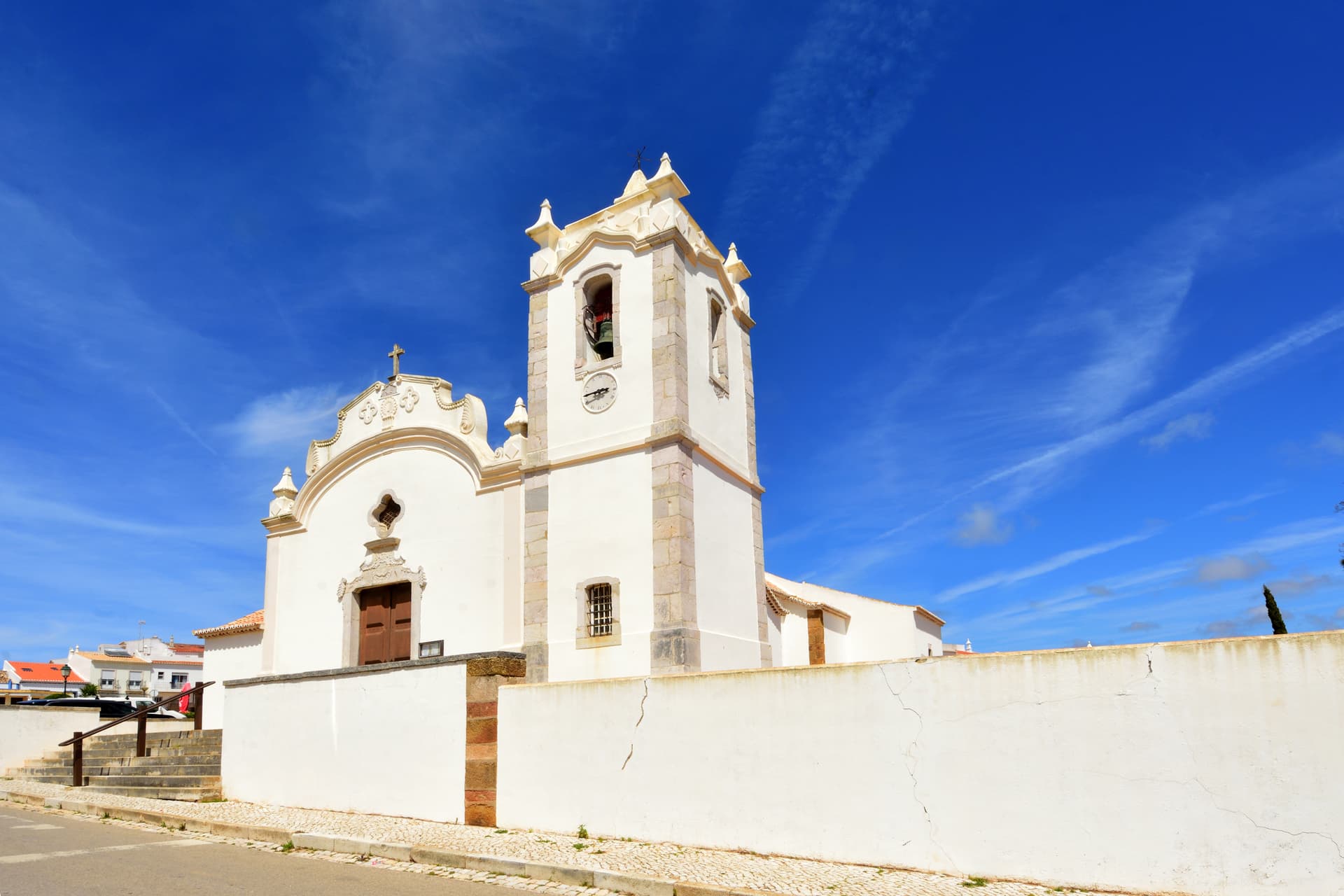 White Mother Church of Vila do Bispo with bell tower under bright blue sky
