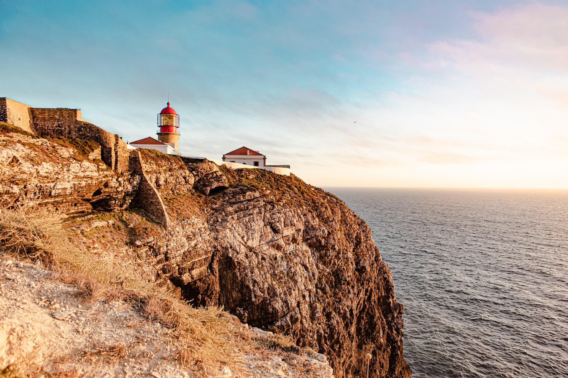 Lighthouse on a cliff overlooking the sea at sunset in Southwest Alentejo and Vicentine Coast Natural Park.