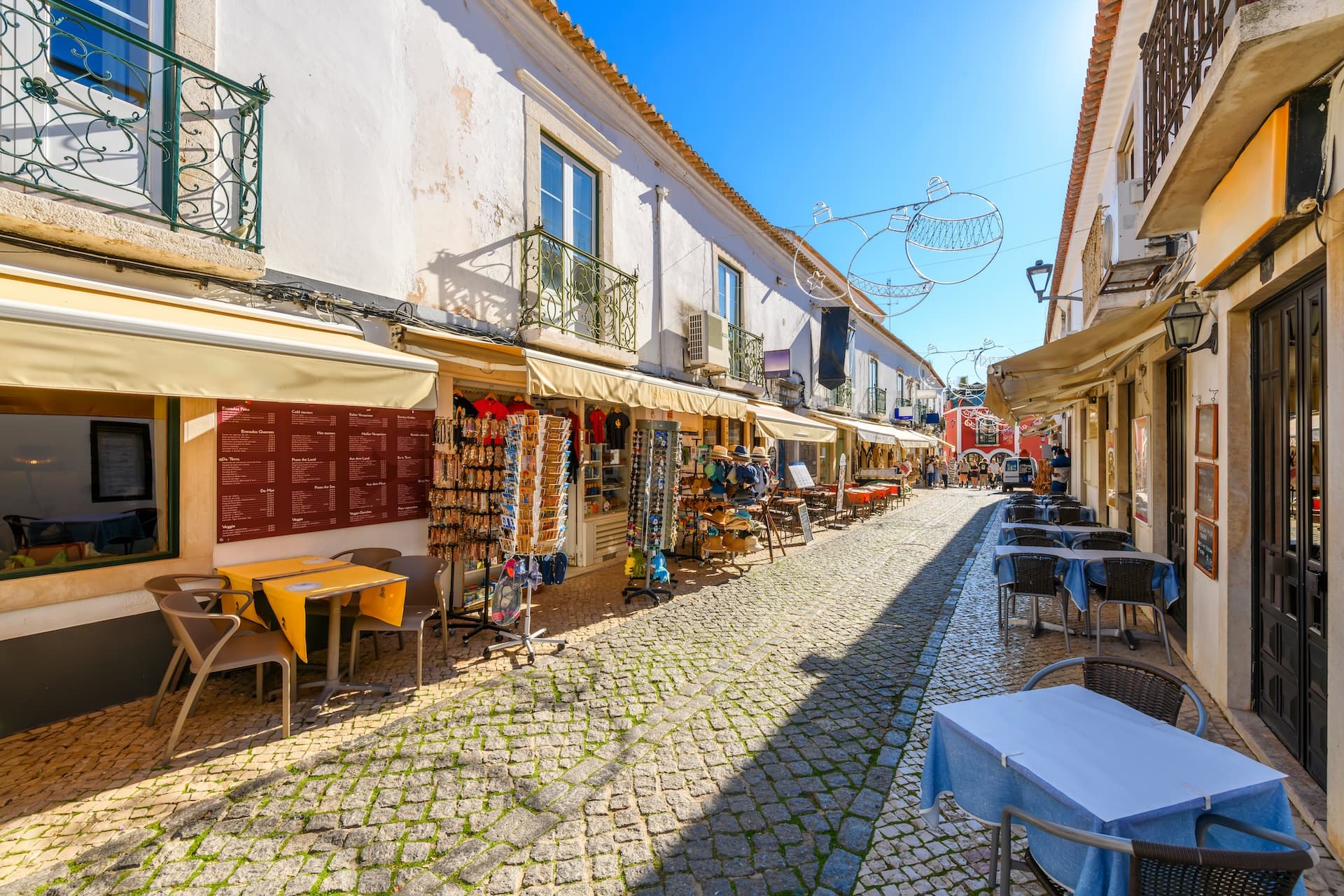 Cobblestone street in the historic old town center of seaside Lagos, Portugal, with shops and outdoor seating.