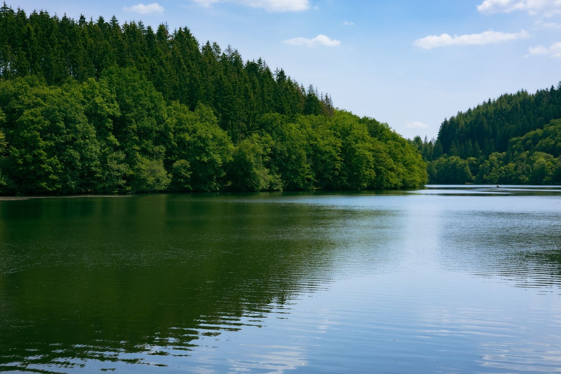 A still crater lake ringed by steep wooded banks