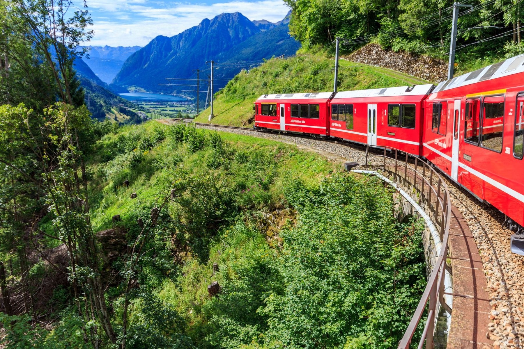 A regional train curving through a green alpine valley