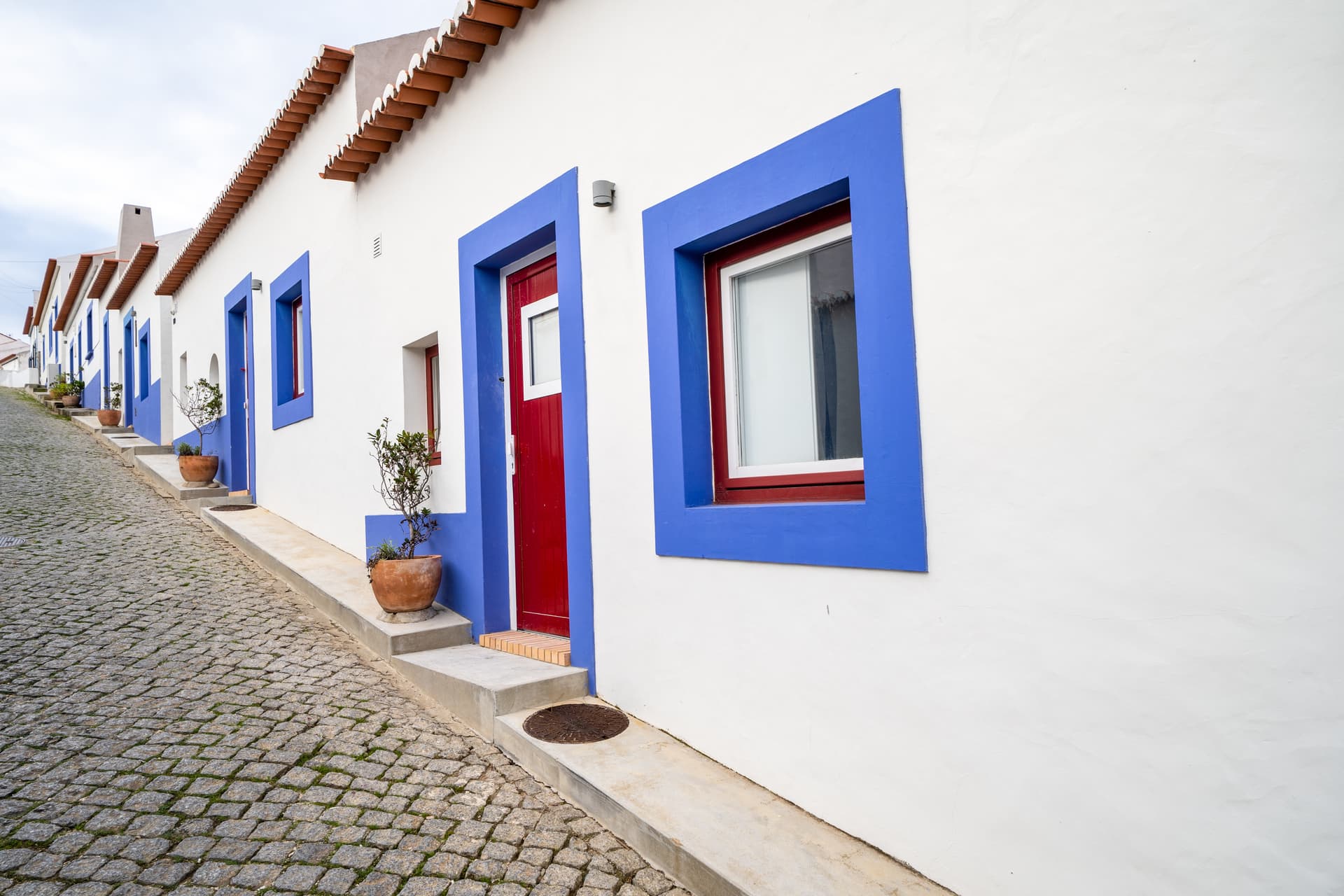 Cobblestone street beside white and blue traditional homes in Odeceixe, Algarve.