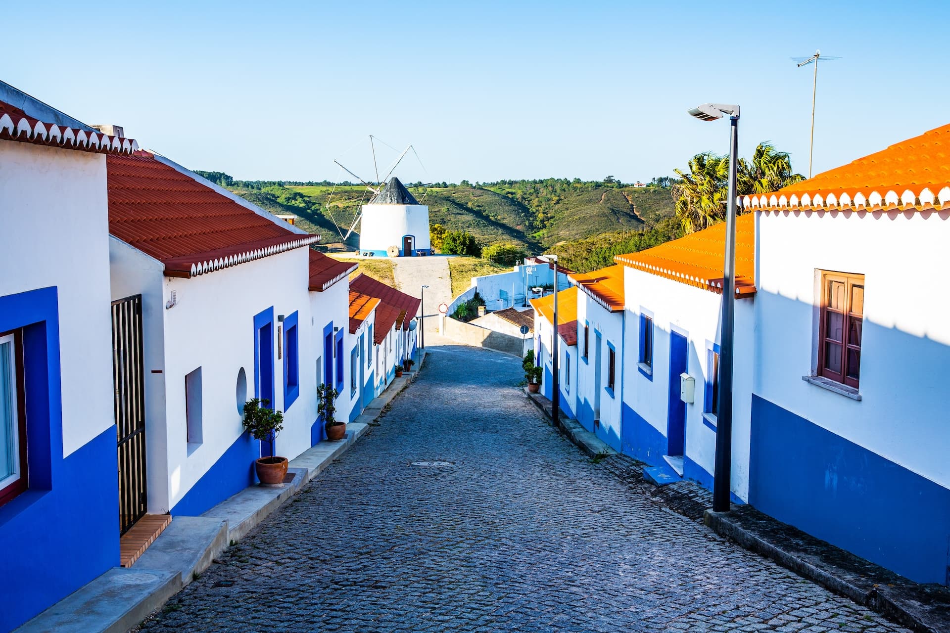 Cobblestone street leading to a white windmill in Odeceixe, Algarve, Portugal.