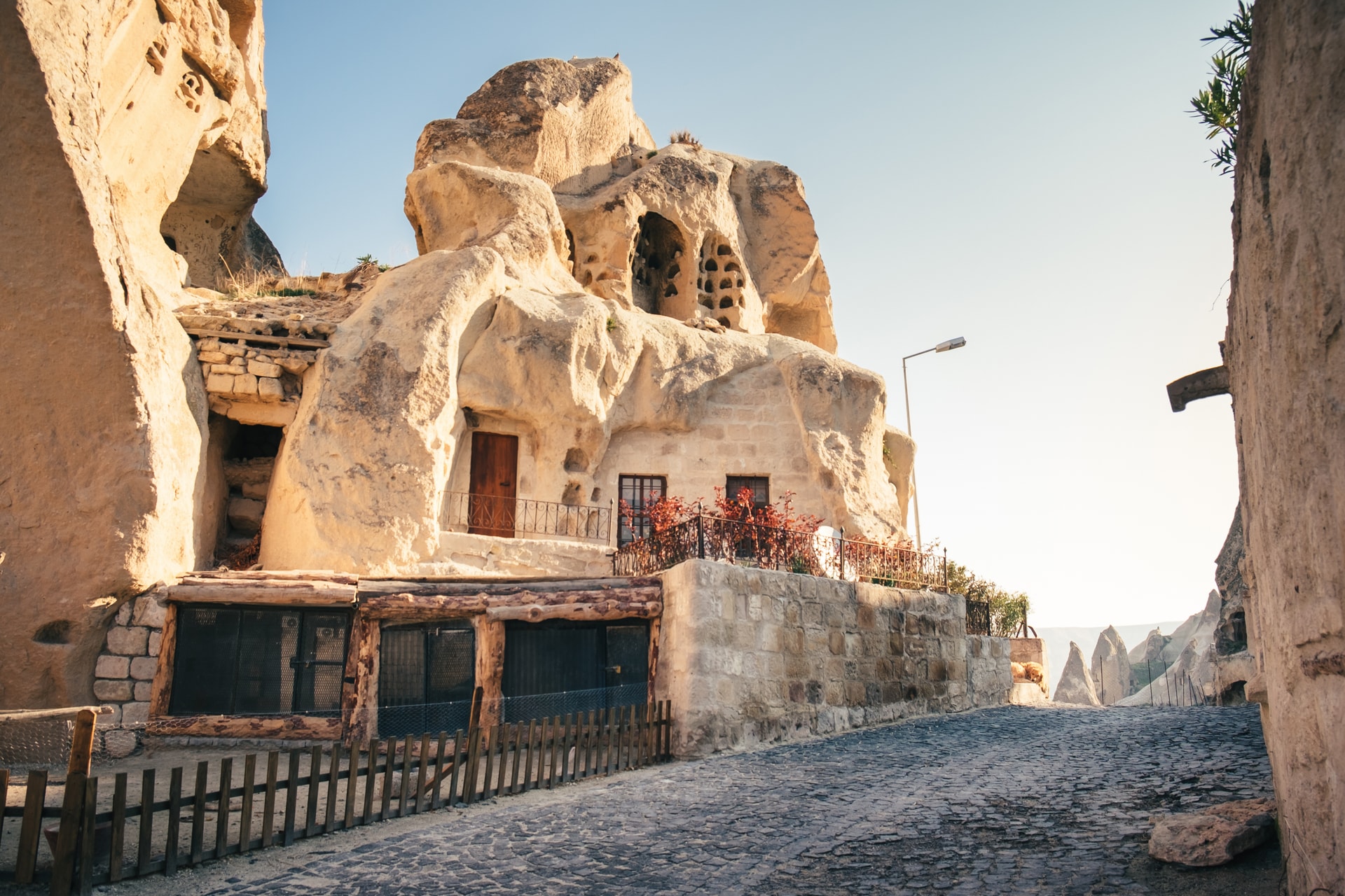Cave dwelling carved into rock face along a cobblestone street in Göreme, Cappadocia.