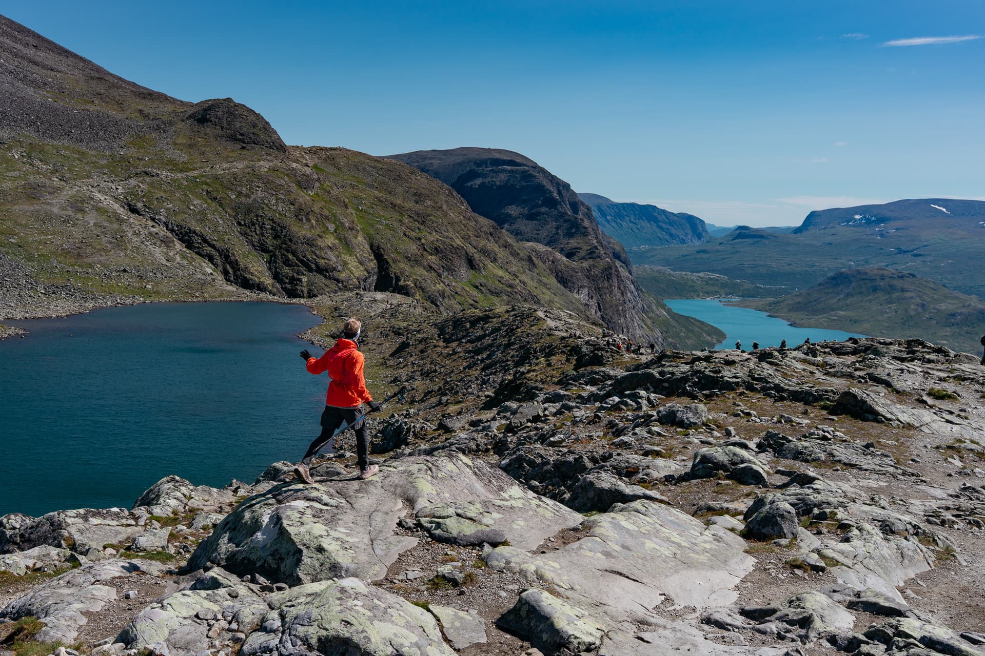 Hiker in orange jacket on Besseggen ridge above Bessvatnet lake