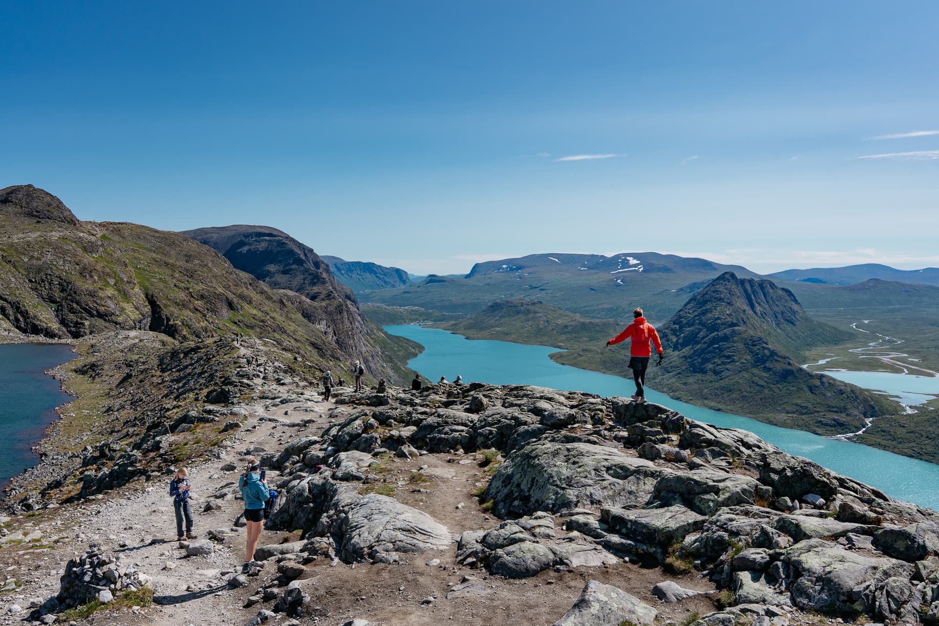 Hikers on Besseggen ridge overlooking turquoise alpine lakes and mountains