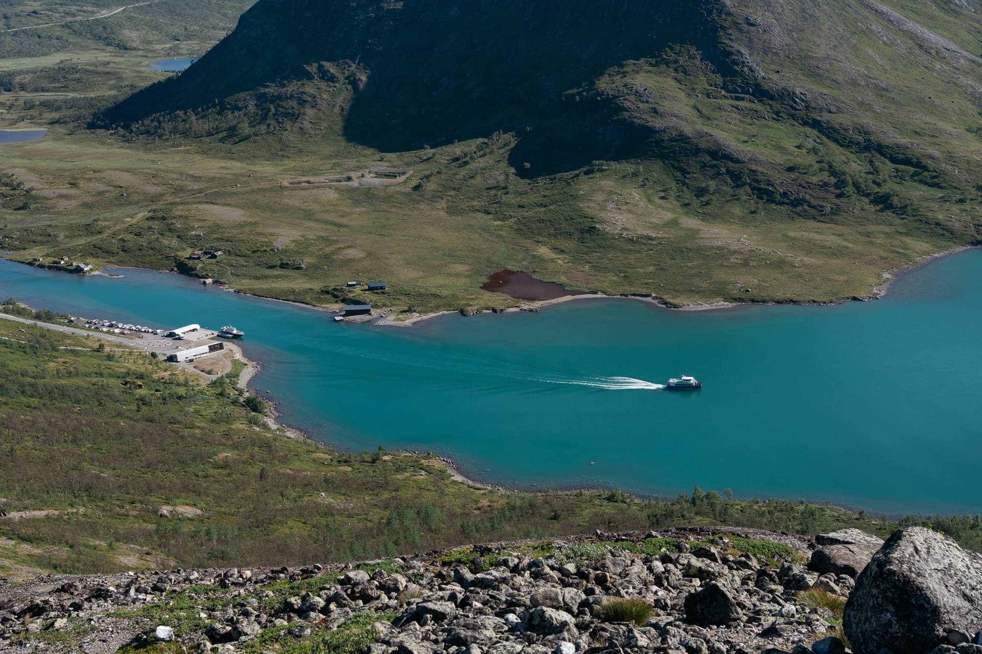 Gjende boat leaving Gjendesheim on turquoise alpine lake with surrounding mountains