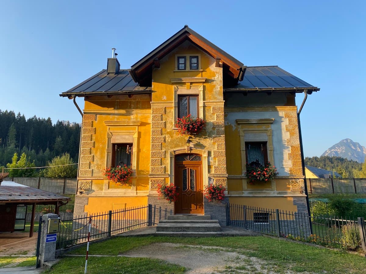 Yellow two-story house with flower boxes and a gabled roof in an alpine setting