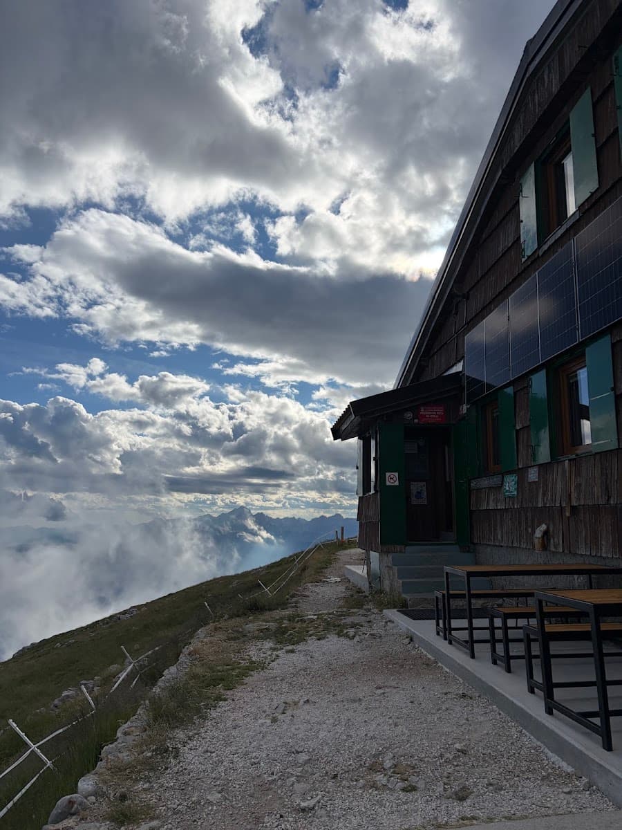 Wooden mountain hut with outdoor seating and cloudy sky over mountain ridge
