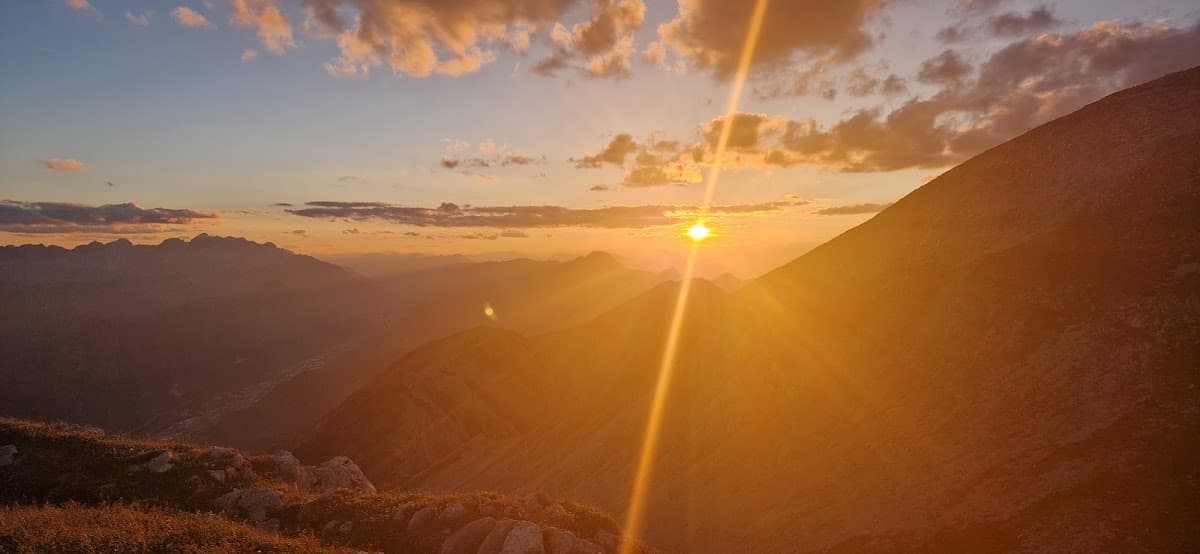 Sunset over mountain peaks with bright sun rays and hazy valleys