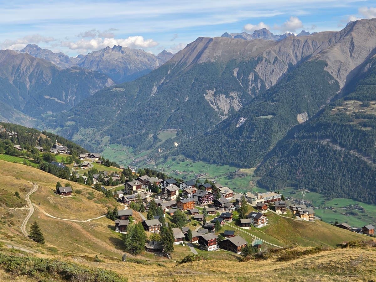 Alpine village nestled in a mountain valley surrounded by peaks and pine forests