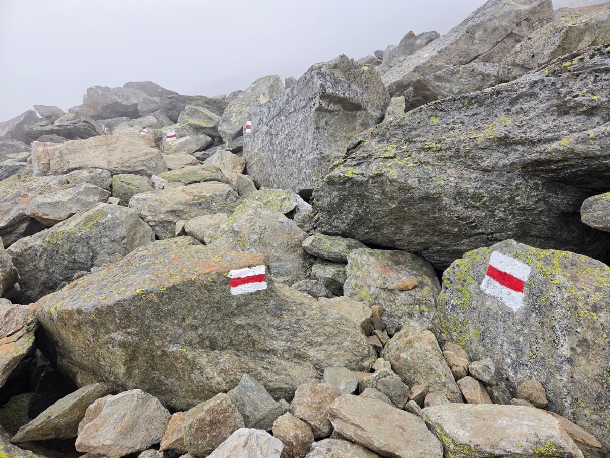 Red and white hiking trail markers painted on rocky mountain terrain