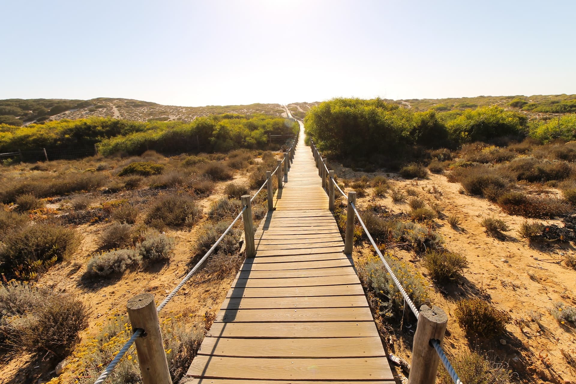 Wooden boardwalk through scrubland and dunes toward Praia do Monte Velho, Santiago do Cacém, Portugal.